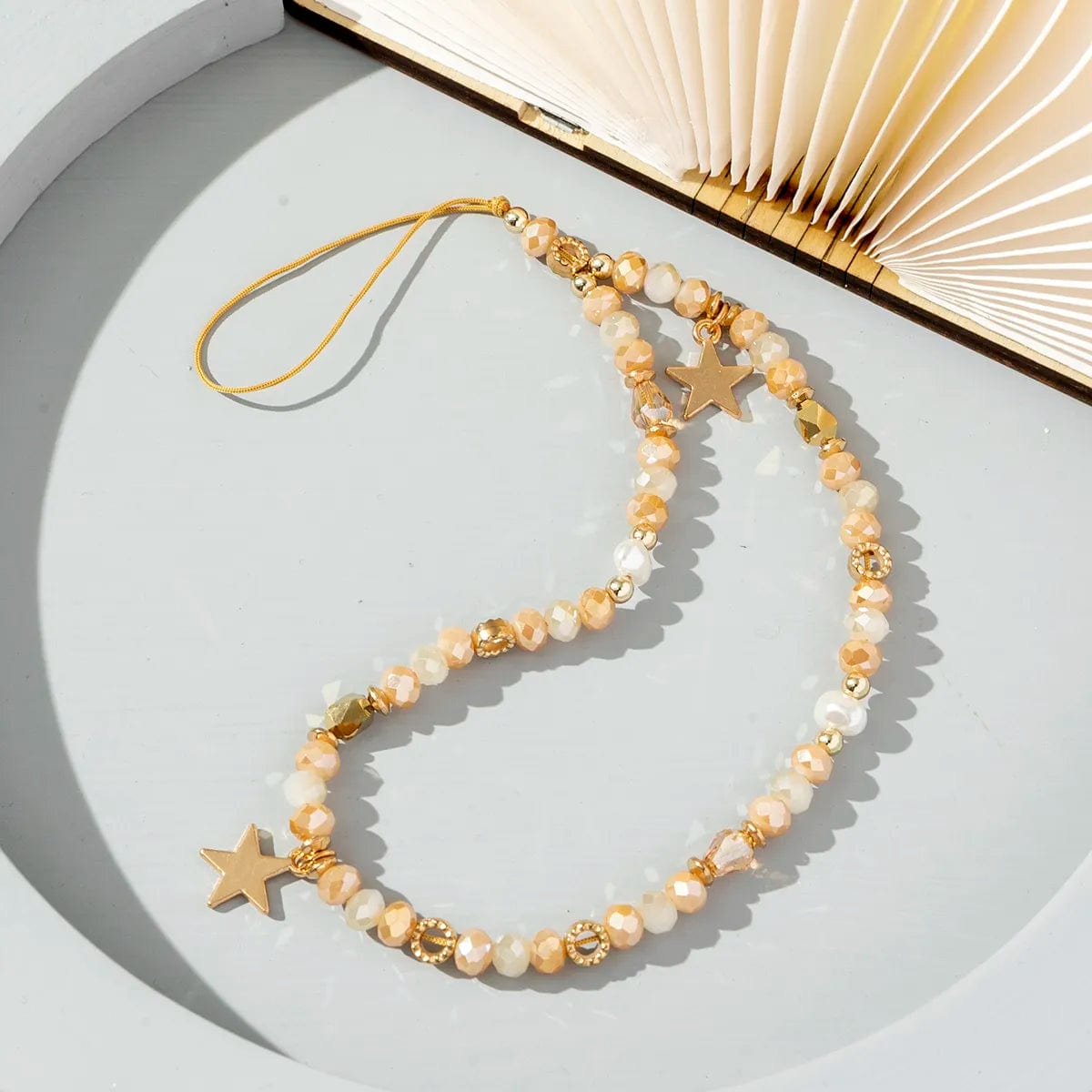 Beigefarbene Handykette mit goldenen Sternen und goldenen Details