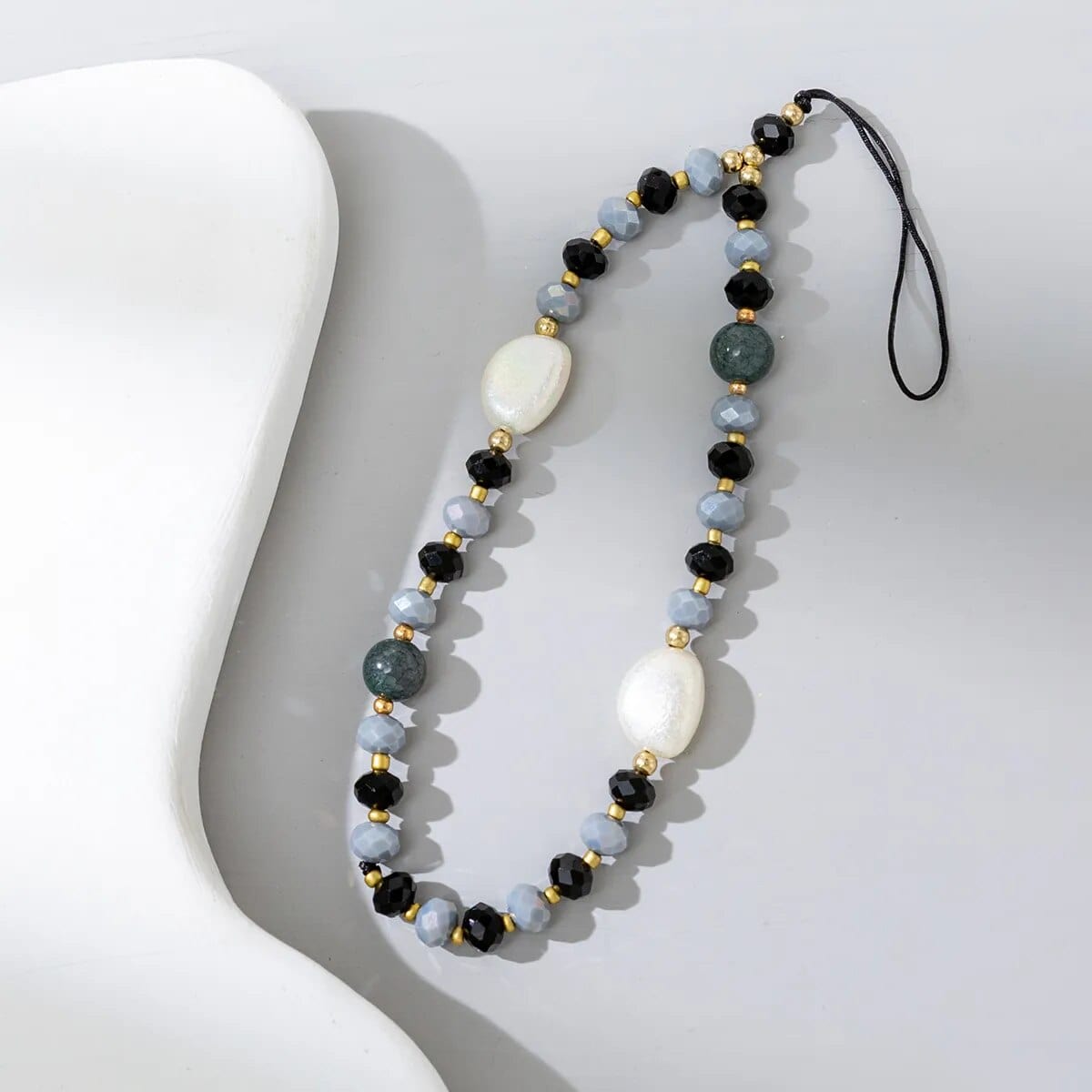 Graue Perlen-Handykette mit dicken weißen Steinen.