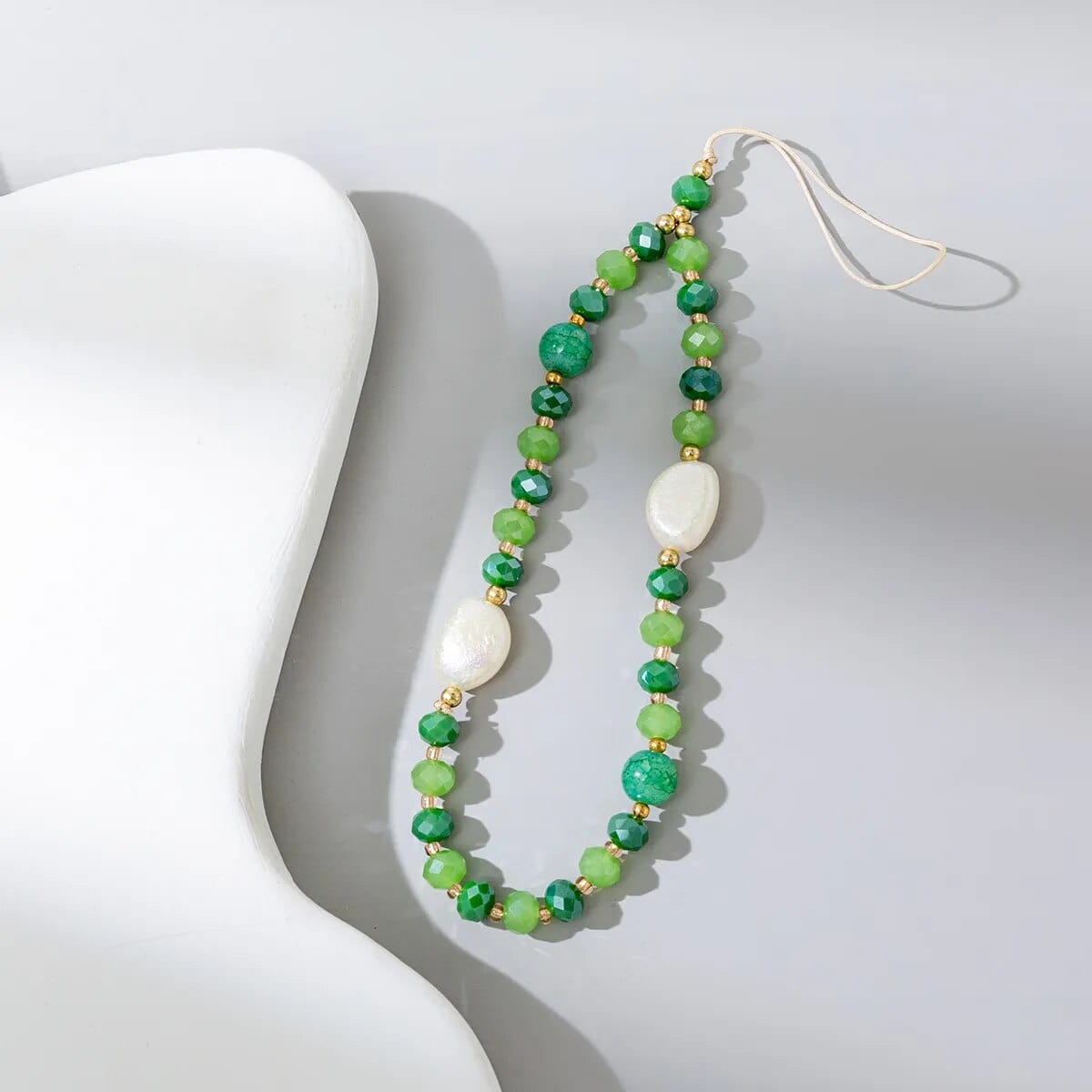 Grüne Perlen-Handykette mit dicken weißen Steinen.