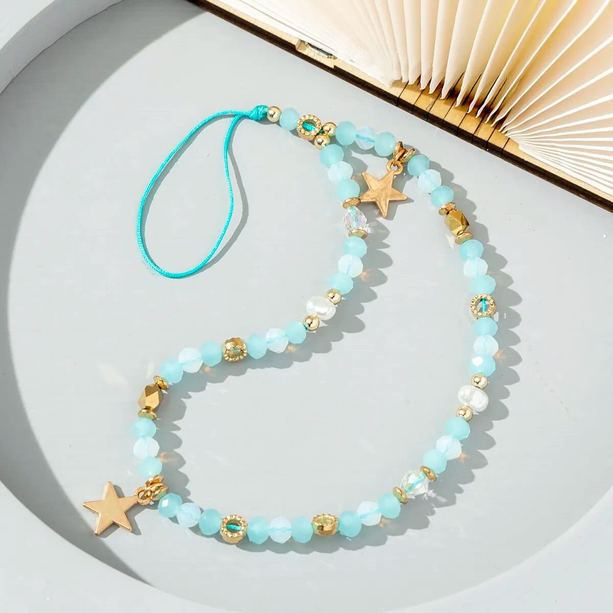 Hellblaue Perlen-Handykette mit goldenen Details