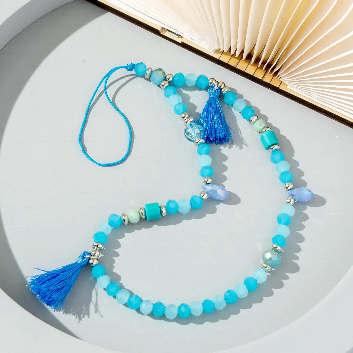 Türkisfarbene Handykette mit blauem Pompons