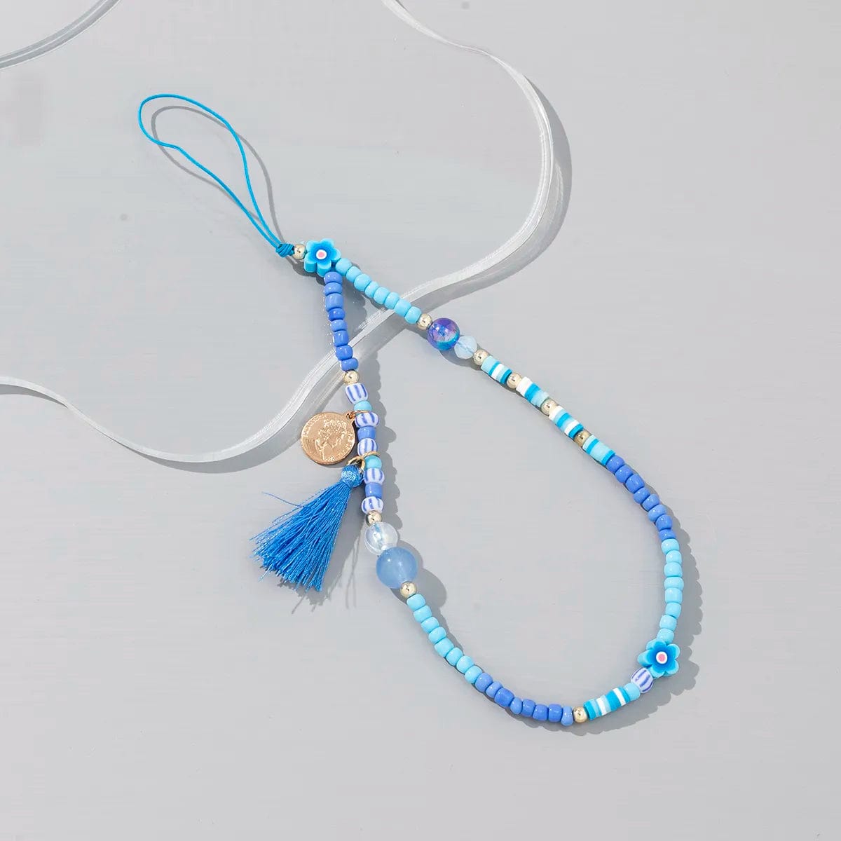Kleine blaue Perlen-Handykette mit Pompons und Mini-Medaille
